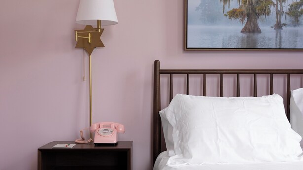 A bedroom with a bed, a nightstand with a lamp, and a framed picture on the wall. - Hotel Klaus (Washington)