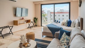 Een moderne hotelkamer met een bed, een bank, een televisie en een balkon met uitzicht op de stad.