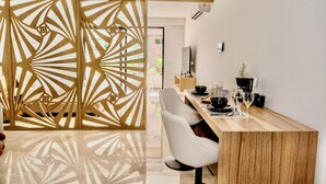 Een moderne eetruimte met een houten scheidingswand, een lange houten tafel, witte stoelen en een aan de muur bevestigde televisie.