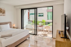 Een moderne hotelkamer met een groot bed, een flatscreen televisie, een balkon met een tafel en stoelen, en uitzicht op het gebouw.
