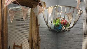 A cozy room with a wooden chair, a radiator, and a shelf with decorative items. - Cosy seaside cottage one minute walk from the beach. Dog friendly! (Cromer)
