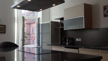 A modern kitchen with a large island, built-in appliances, and a view of a brick building.