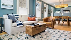 A living room with a sofa, a leather armchair, a wooden coffee table, and a patterned rug. - Workspace | Soaking Tub | W/D | 5 Min Downtown (Portland)