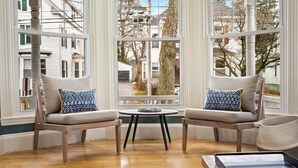 A cozy room with two armchairs, a small round table, and a view through large windows. - Workspace | Soaking Tub | W/D | 5 Min Downtown (Portland)