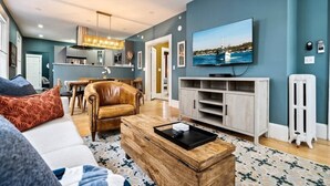 A modern living room with a sofa, coffee table, and a TV mounted on the wall. - Workspace | Soaking Tub | W/D | 5 Min Downtown (Portland)