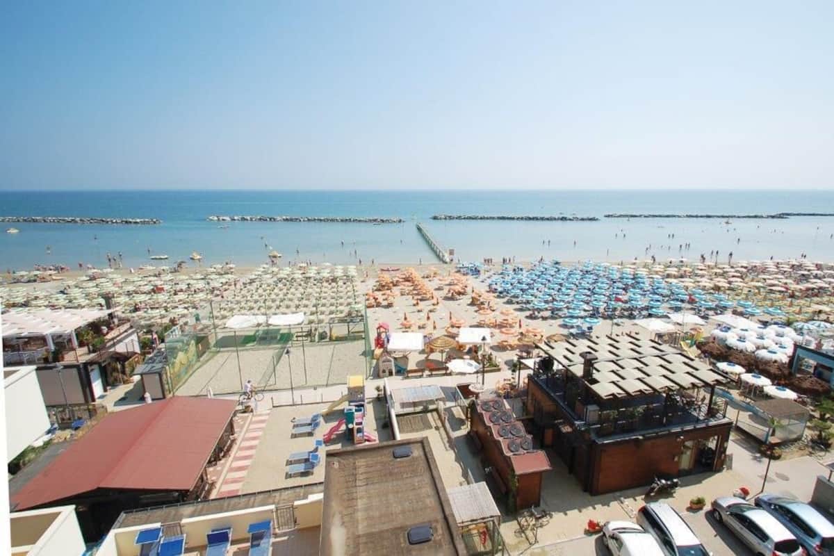 A beachside hotel with multiple rooms, a pool, and a view of the sea.