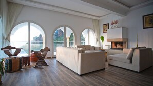 A spacious living room with a large sofa, a smaller sofa, and a coffee table. There are three large windows providing a view of the outdoors. - Magnifique Villa Avec Piscine et vue sur mer & Montagnes (Béja Governorate)