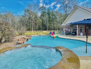 A swimming pool with a hot tub, surrounded by a wooden deck and a brick building. - Country Getaway Magnolia Forest Home in10 Acre Lot (Magnolia)