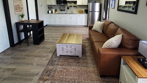 A modern kitchen with white cabinets, stainless steel appliances, and a dining area with a black table and chairs. - Charming building with 1 bedroom and AC, WiFi in serene Whitehall (Whitehall)
