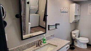 A modern bathroom with a granite countertop sink, a mirror, a toilet, and a cabinet. - Charming building with 1 bedroom and AC, WiFi in serene Whitehall (Whitehall)