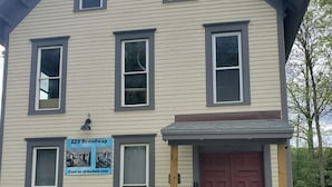 A two-story building with a red door and a sign advertising Airbnb availability. - Charming building with 1 bedroom and AC, WiFi in serene Whitehall (Whitehall)