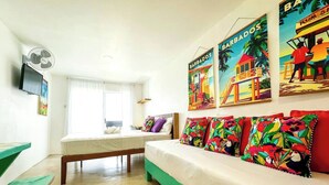 A room with a bed, a desk, a chair, and a TV mounted on the wall. - Studio APT 4B, Oceanview + Pool, Near Beach  @ Paradise Point Barbados (Oistins)