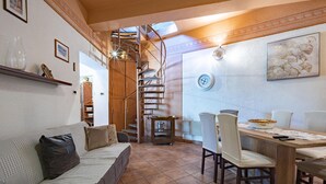 A cozy living area with a sofa, a dining table with chairs, a staircase, and a wall clock. - Stunning home in Rijeka with WiFi (Rijeka)