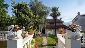 A villa with a stone pathway leading to the entrance, surrounded by lush greenery and decorative swans. - Stunning home in Rijeka with WiFi (Rijeka)