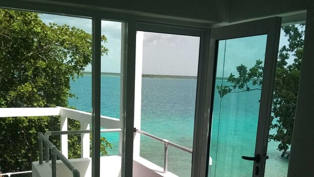 A balcony with a view of the ocean and a chair. - ZENSUS LAGUNA (Bacalar)