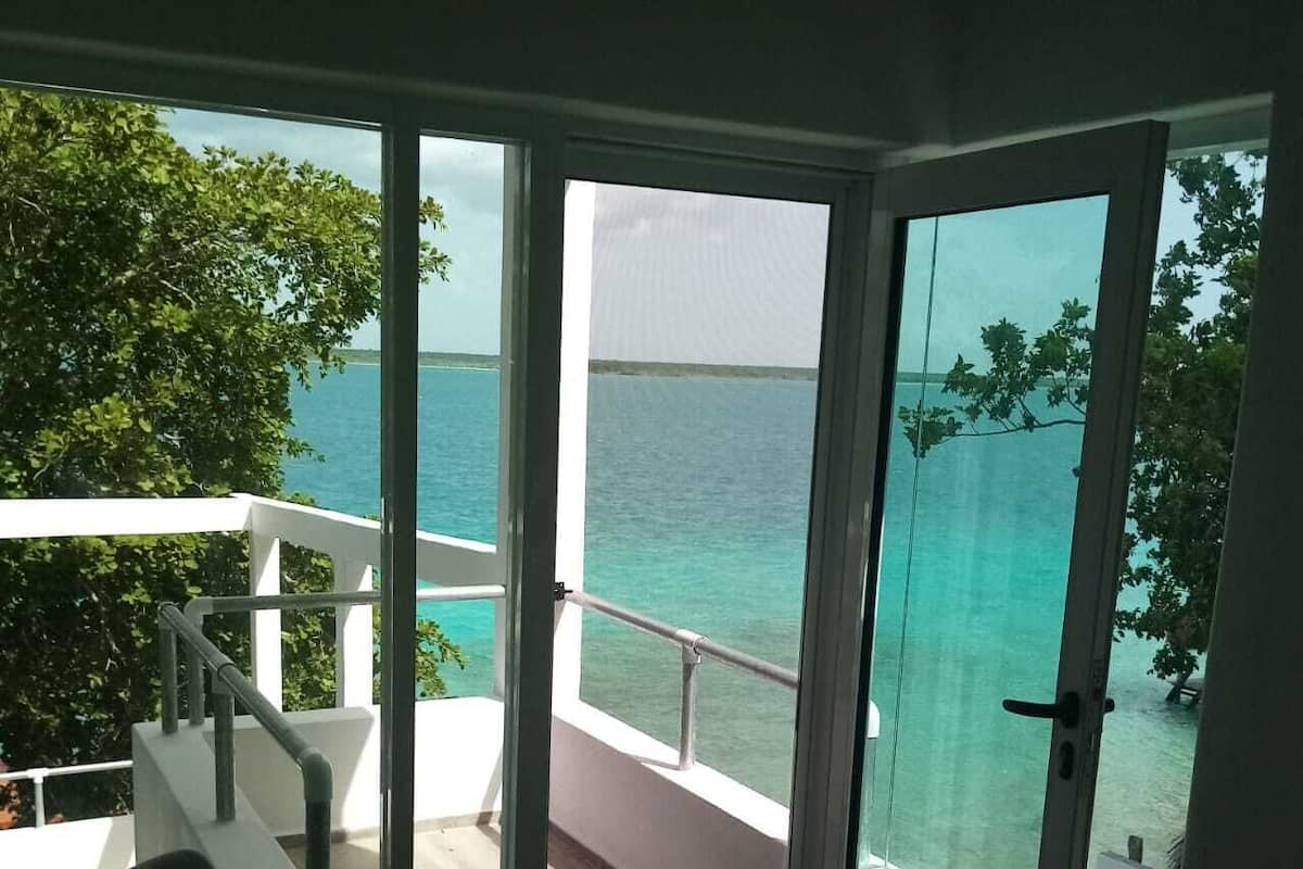 A balcony with a view of the ocean and a chair.