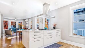 Una cocina moderna con armarios blancos, una isla central y un ventanal con vistas.