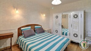 Een slaapkamer met een bed, nachtkastjes, een kledingkast en een hanglamp.