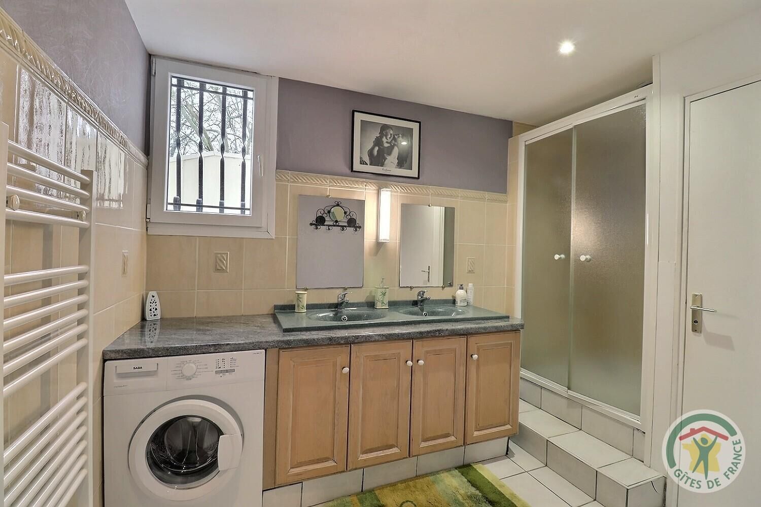 Un bagno moderno con lavatrice, due lavandini, uno specchio grande e una doccia.