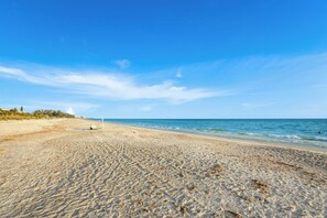 A sandy beach with a clear blue sky and calm sea. - Turtle Walk - Walk to Gorgeous Beach! WALK to 12 different Restaurants! (Longboat Key)