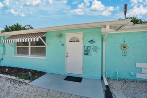 A turquoise house with a white door, a striped awning, and a small garden area with stepping stones. - Turtle Walk - Walk to Gorgeous Beach! WALK to 12 different Restaurants! (Longboat Key)