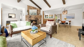 A spacious living room with a stone fireplace, leather sofas, and a dining area with a view. - Russian River Wine Country Retreat Near Healdsburg: Pool, AC & EV Charger (Forestville)