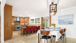 A spacious kitchen with wooden cabinets, a dining area with a table set for six, and a large window providing a view of the outdoors. - Russian River Wine Country Retreat Near Healdsburg: Pool, AC & EV Charger (Forestville)