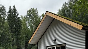 A small cabin with a wooden deck, a covered seating area, and a large sliding glass door.