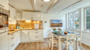 Eine Küche mit Holzschränken, einem Spülbecken und einem Essbereich mit Tisch und Stühlen.