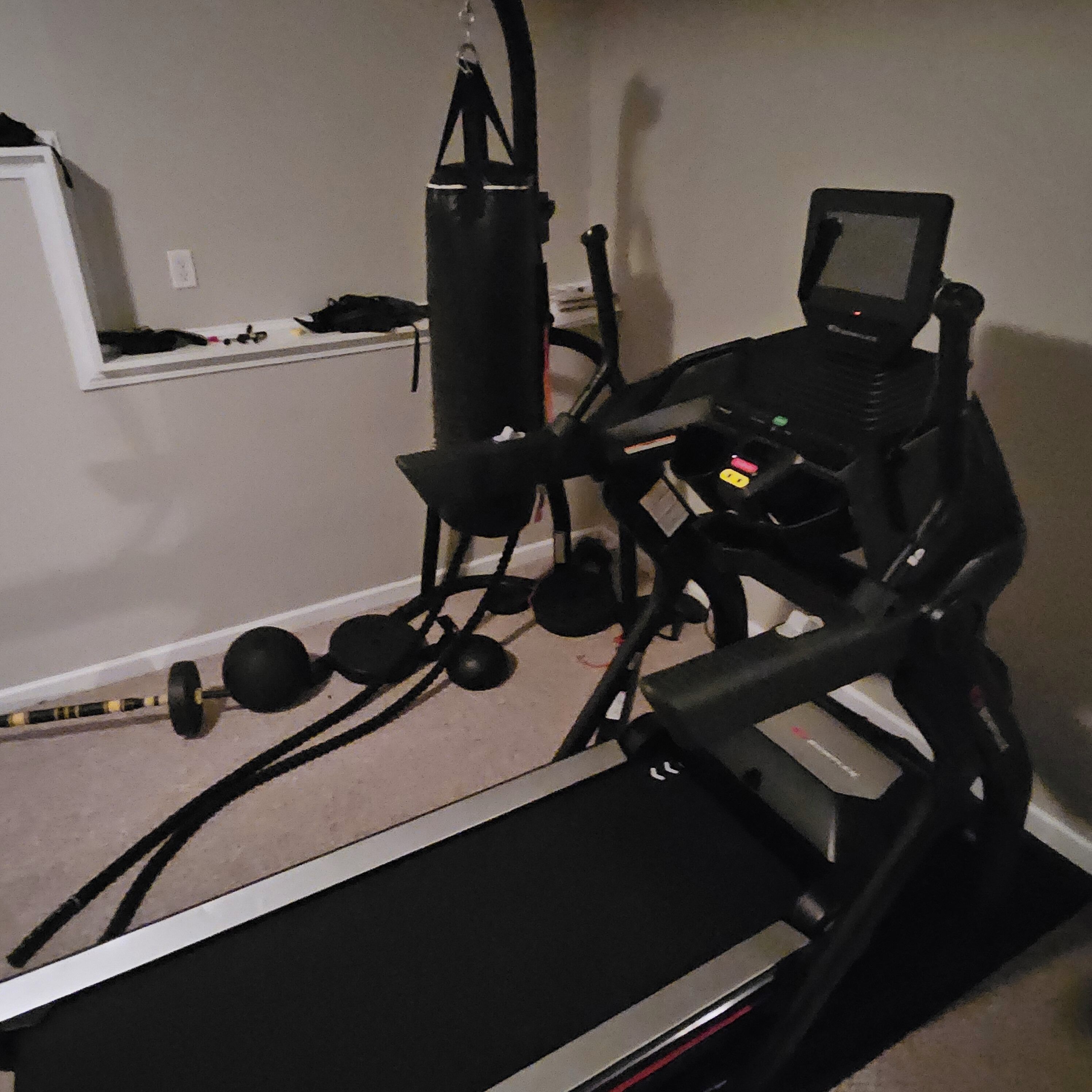 Gimnasio en casa equipado con cinta de correr, pesas y bicicleta estática.