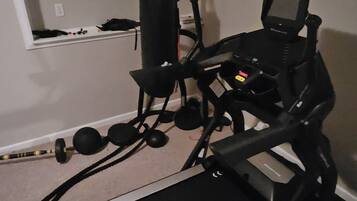 Gimnasio en casa equipado con cinta de correr, pesas y bicicleta estática.