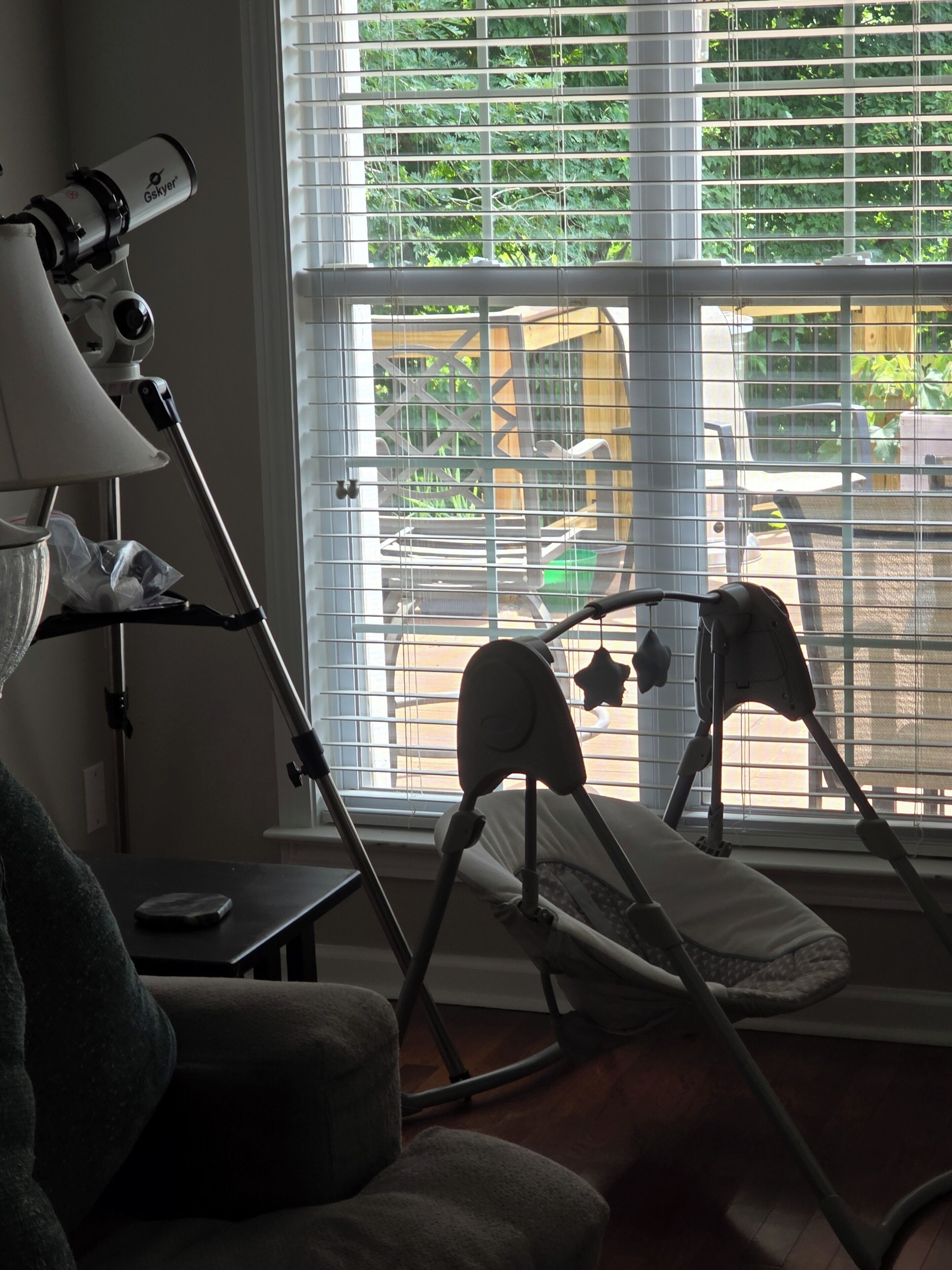 A room with a telescope, a chair, and a window with blinds.