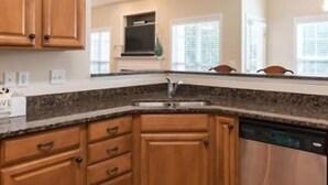 Una cocina con armarios de madera, encimera de granito y lavavajillas.
