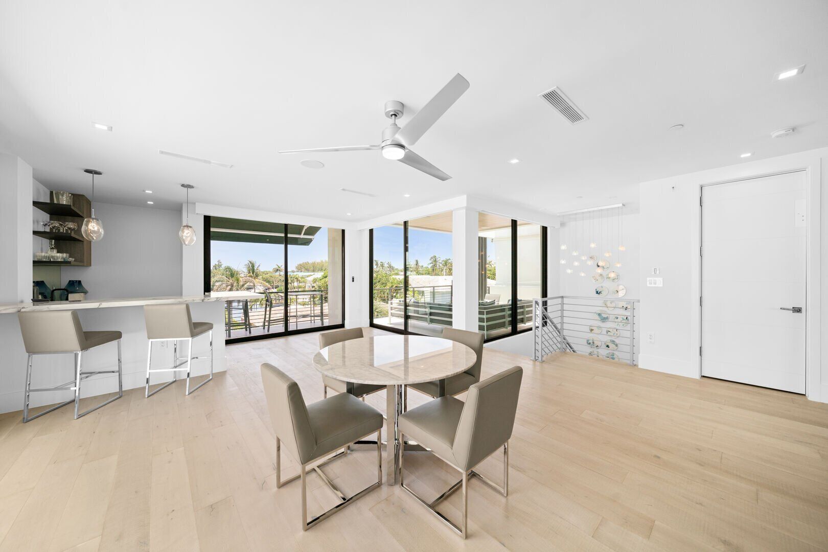 Una cocina moderna con barra, ventanas amplias y un comedor con mesa redonda y sillas.