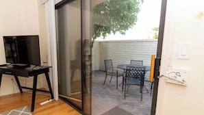 Ein Zimmer mit einer Schiebetür und Zugang zu einer Außenpatio-Terrasse mit Tisch und Stühlen.