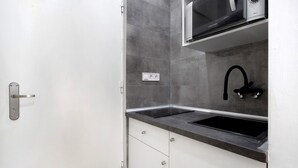 Een keuken met een magnetron, spoelbak en kastjes.