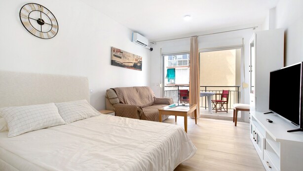 Een hotelkamer met een bed, een bank, een televisie en een balkon met uitzicht.