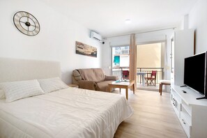 Ett hotellrum med en säng, en soffa, en tv och en balkong med utsikt.