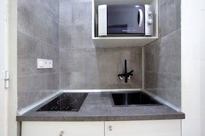 A kitchen with a built-in microwave, a black induction cooktop, and a sink.