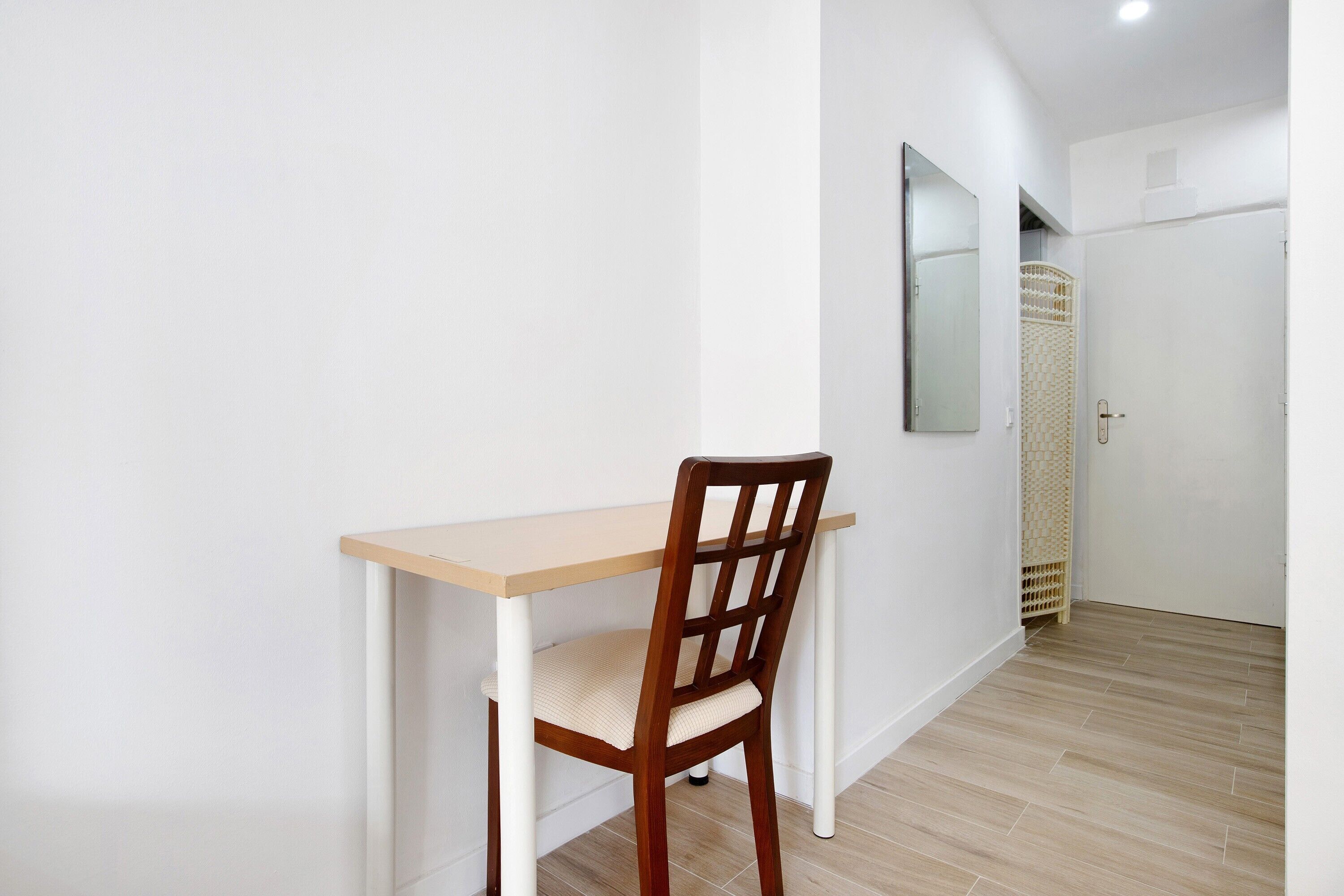 Ein Zimmer mit einem Holzbett, einem Tisch und einer weißen Wand.