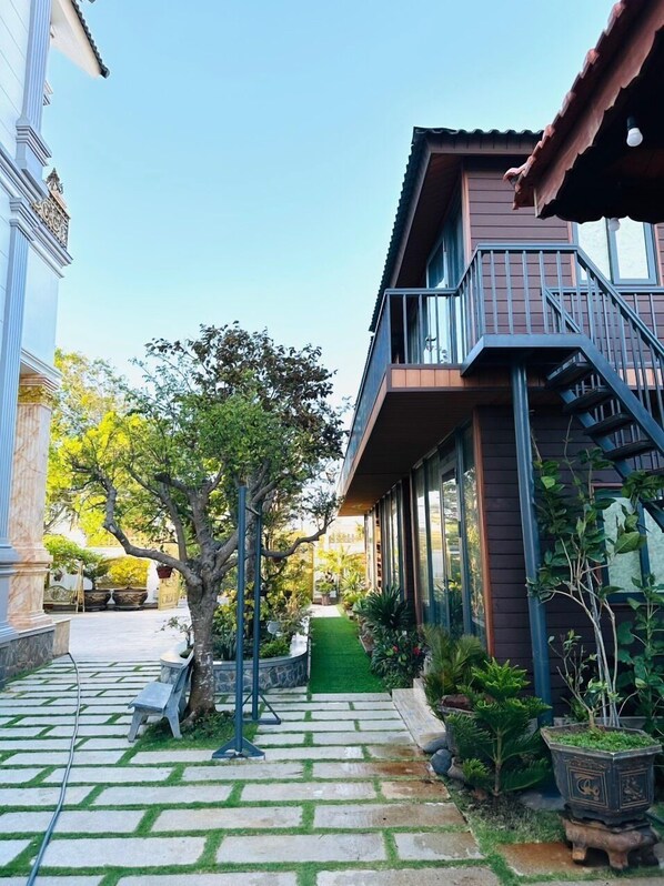 Un bâtiment moderne doté d’un balcon, d’un chemin en pierre et d’une végétation luxuriante.