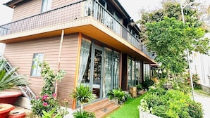 Ein zweistöckiges Haus mit Balkon, einem kleinen Garten und einem Weg zum Eingang.