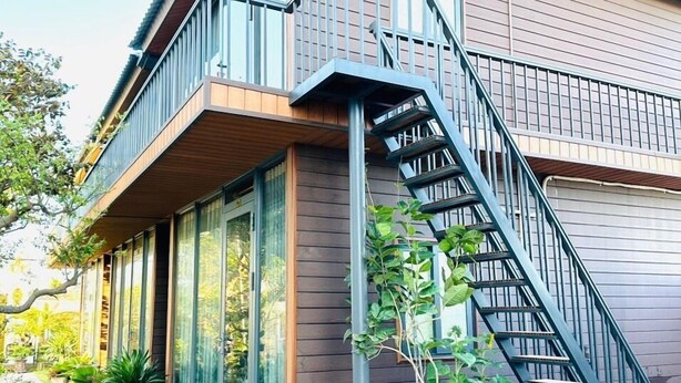 Ein zweistöckiges Haus mit einem Balkon und einer Treppe, die zu der oberen Etage führt.