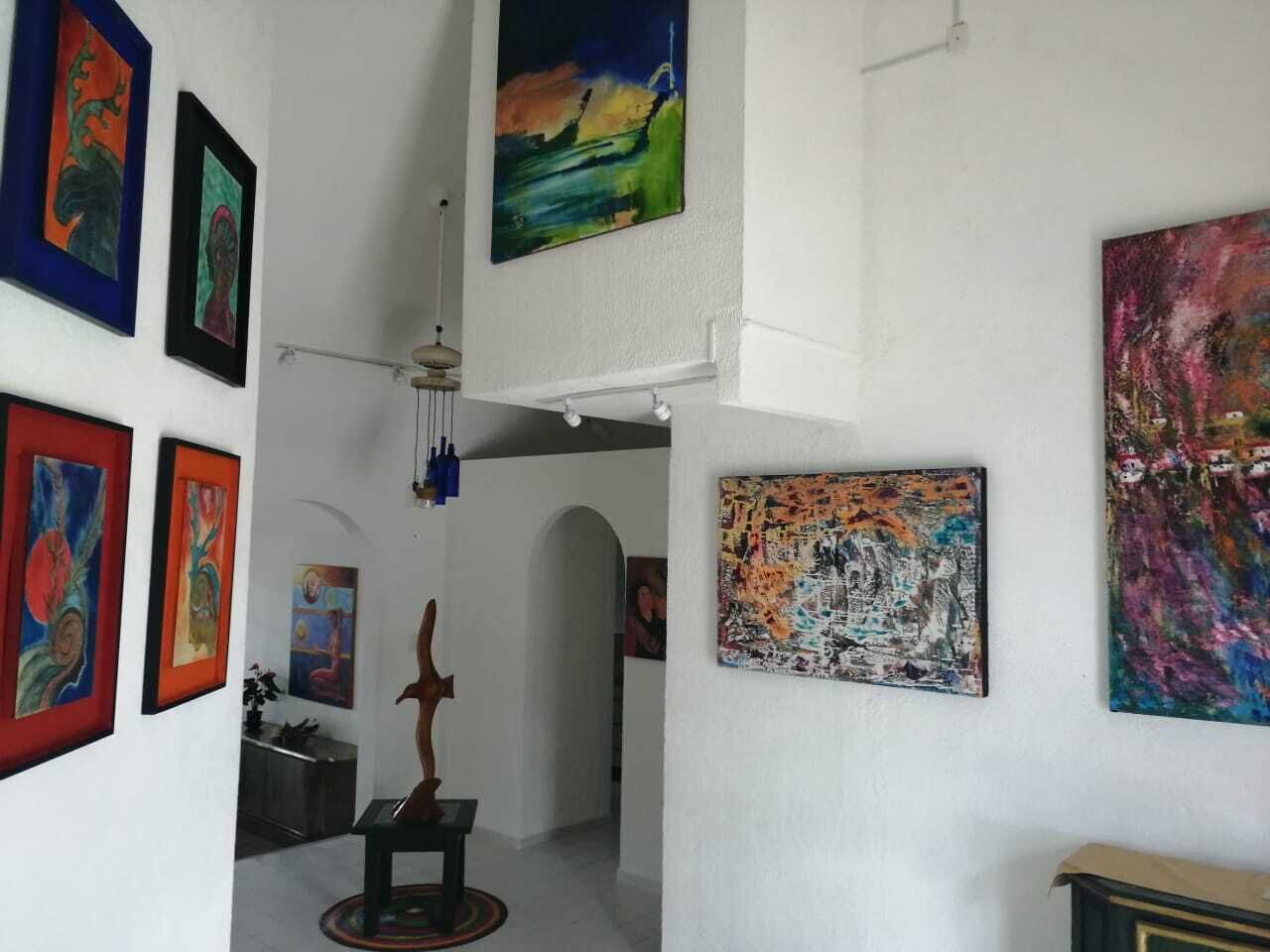 A hallway with various artworks on the walls, a wooden sculpture, and a ceiling fan.
