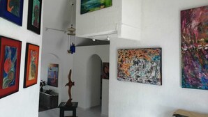 A hallway with various artworks on the walls, a wooden sculpture, and a ceiling fan. - Casa, "Joy of the Sea" (Puerto Morelos)