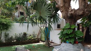 A wooden table with blue chairs in a garden area with a large tree and various plants. - Casa, "Joy of the Sea" (Puerto Morelos)