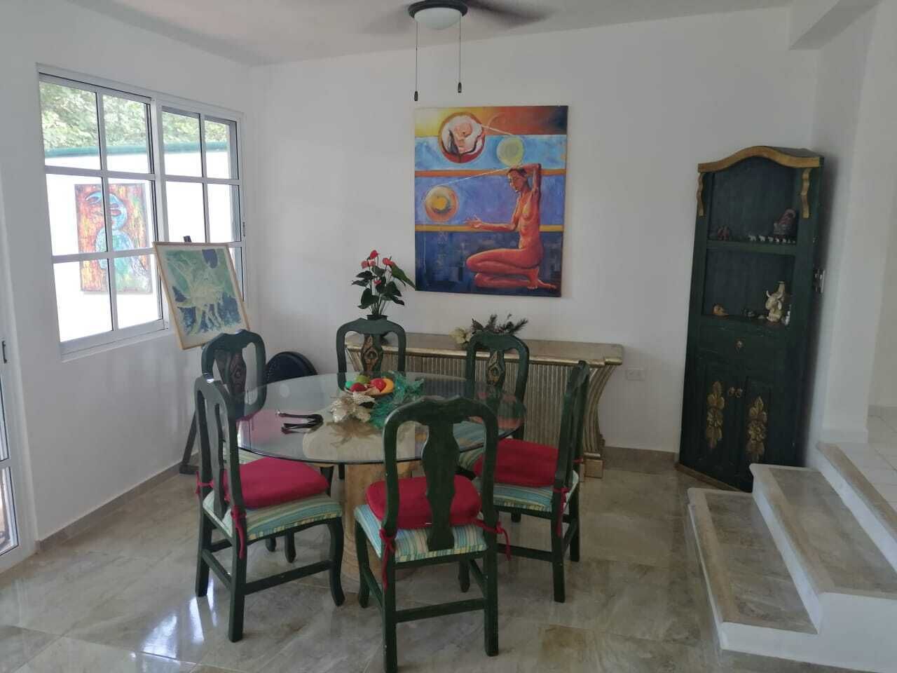 Ein Essbereich mit einem runden Tisch, vier Stühlen und einem Bild an der Wand.