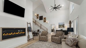Ein geräumiges Wohnzimmer mit Kamin, Korbmöbeln und einer Treppe zu einer oberen Ebene.