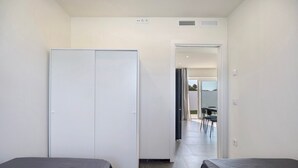 Ein Hotelzimmer mit zwei Betten, einem Kleiderschrank und Blick auf einen Speisesaal.