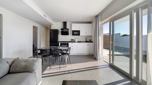 Eine moderne Wohnung mit Essbereich, einer Küchenzeile und großen Schiebegläsern zum Balkon.